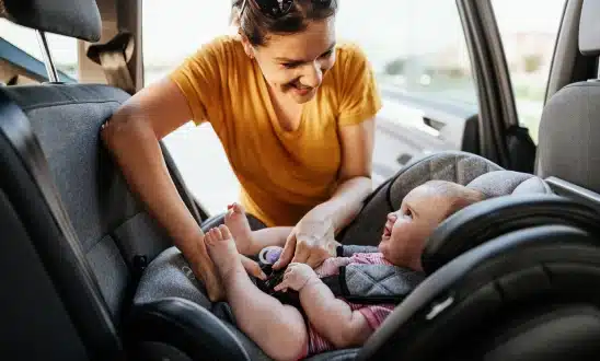 Mother securing her baby in a rear-facing car seat