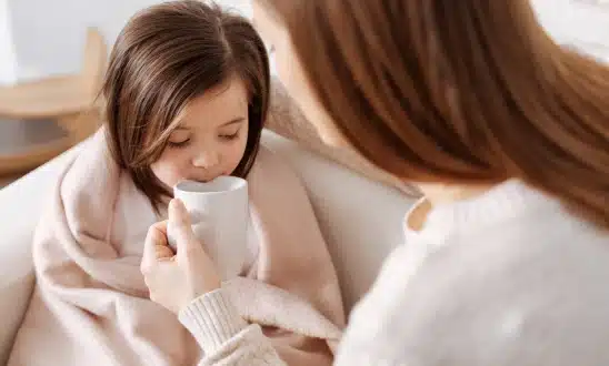 Child drinking from a cup while wrapped in a blanket