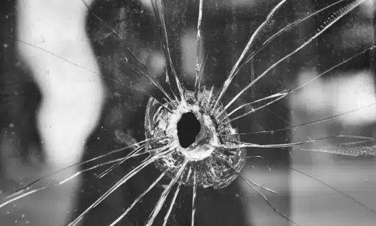 Bullet hole in a shattered glass window