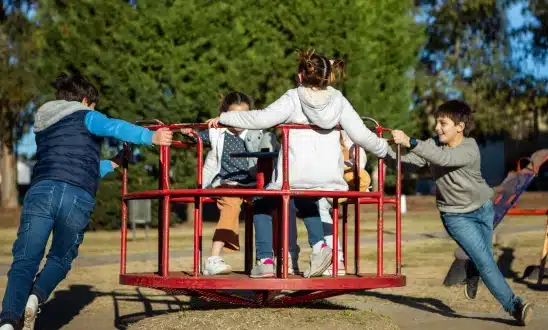 Children playing on a spinning playground merry-go-round