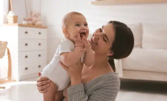 Mother holding a smiling baby at home